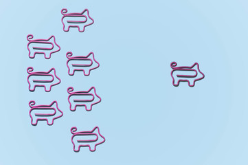 top view of pink piggy paper clips in one direction with leader isolated on purple, leadership concept