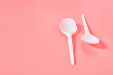 Two white disposable spoons on pink background. Concept of save environment, ecology, recreation on picnic, party and other events. Copy space