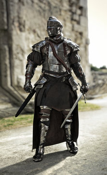 Brave medieval knight standing guard in a full suit of armor and holding a sword in defense of his castle. 3d rendering