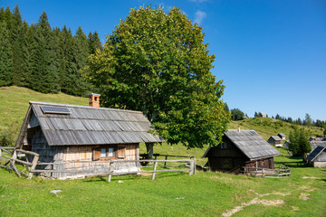 Beautiful view of traditional wooden cabins in the idyllic Slovenian mountains.