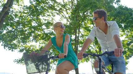 CLOSE UP: Young woman smiles at boyfriend while riding bikes around the park.