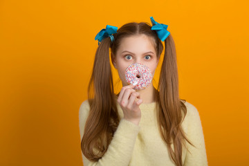 beautiful young woman with long hair on a yellow background with a donut in hand