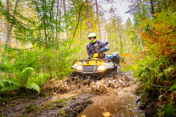 ATV rides through the mud bottom view. Yellow ATV below. Sprays fly from under the wheels of the quad bike. Overcoming obstacles on the road. Concept - sale of ATVs. Extreme sports. Relaxation. Race © Grispb