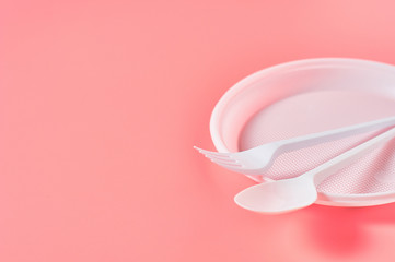 Disposable plastic utensils scattered on pink background. Concept of save environment, ecology, recreation on picnic, party and other events. Copy space