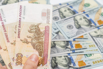 A hand holding one hundred ruble and american dollar banknotes on background, ruble devaluation and usd-rub exchange rate concept