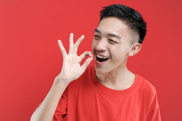 Young handsome Asian man showing ok sign or yummy pose with fingers