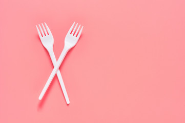 White disposable forks scattered on pink background. Concept of save environment, ecology, recreation on picnic, party and other events. Top view. Copy space