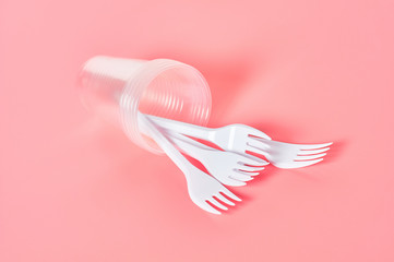 Disposable plastic utensils on pink background. Concept of save environment, ecology, recreation on picnic, party and other events