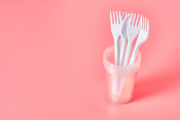 Disposable plastic utensils on pink background. Concept of save environment, ecology, recreation on...