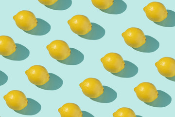 Isometric pattern from a lot of whole juicy lemons with shadows on a light blue turquoise background. Print on fabric, wrapping paper. Fruit summer backdrop, photo collage. Minimal food texture.