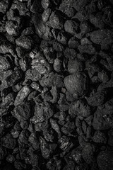Black and dark grey shiny rocks texture background. Raw materials and Industrial coals anthracite, lignite, bituminous coal, asphalt, stone coal. Concept of mining industry, energetics and metallurgy.