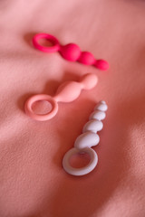 Multicolored erotic toys for pleasure on pinking fabric. Sex gadgets and masturbation devices for adults. Pink and purple rubber anal plugs. Sex shop concept.