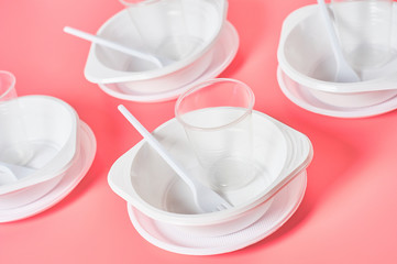 Disposable plastic utensils on pink background. Concept of save environment, ecology, recreation on picnic, party and other events