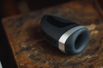 Sex toy for men. Artificial vagina for masturbation. A black sex toy for fap lies on a wooden table...