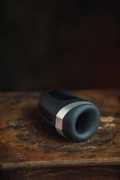 Sex toy for men. Artificial vagina for masturbation. A black sex toy for fap lies on a wooden table top. Sex shop for adults. Penis stimulator.