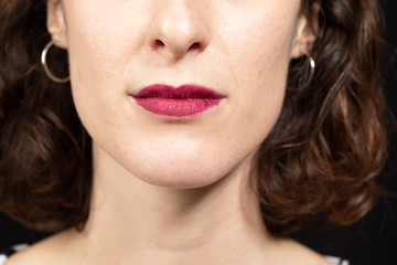 Beautiful brunette women face detail with sensual lips with red matt lipstick. Cosmetology, drugstore and fashion makeup concept...