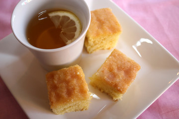 A cup of tea with a slices of lemon drizzle cake