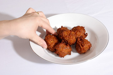 A hand taking a large Indian onion bhajis