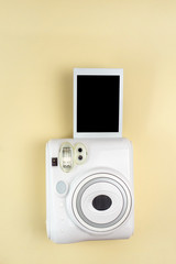 Modern polaroid camera, photo yellow background.