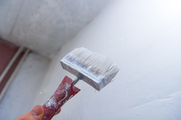 paint brush with a white paint primer - wall painting, apartment repair.