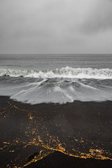 View of volcanic black sand beach and the ocean waves near Vik, South Iceland, summer time