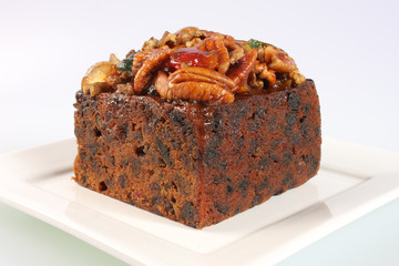 A small rich fruitcake photographed against a white background