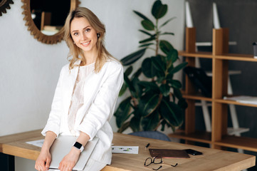 The young woman in the office. Attractive young blonde woman in stylish formal clothes is standing...