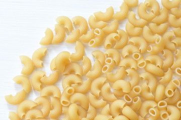 Italian short pasta, on white wooden background