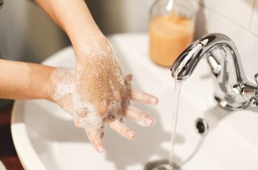 Washing hands. Hands washing with soap foam on background of water flowing from faucet. Prevention...