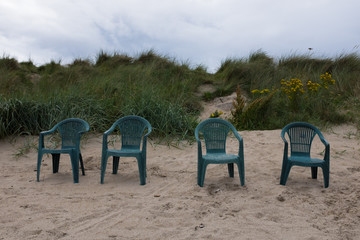Four green lawn chairs on a beach