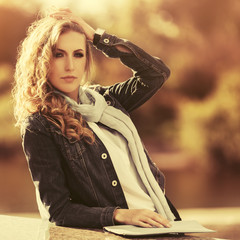 Young fashion blonde woman in denim jacket and light gray scarf