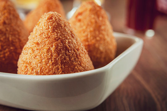 Coxinha de frango (Brazilian appetiser stuffed with chicken) in close up with a pepper sauce