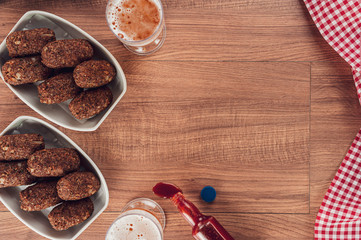 Top view of table with beer, brazilian appetiser kibbe and pepper sauce