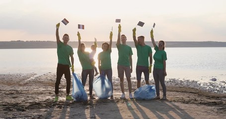 A group of people in green T-shirts stand together and raise the flags of the European Union. European Pollution Control Program. - Powered by Adobe