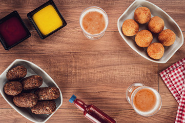 Top view of table with beer, brazilian appetiser coxinha de frango and kibbe