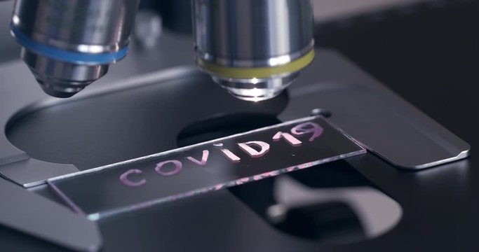 COVID19 under the microscope, the inscription "coronavirus" in abbreviated form, the movement of the slide under the microscope.
