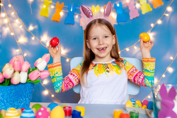 Happy easter! Girls with rabbit ears paints eggs.
