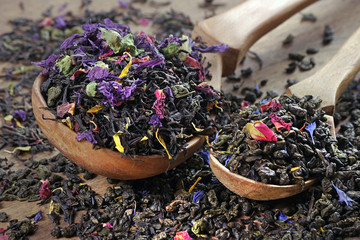 blended tea. black and green tea with dry flower petals and fruits. dry tea leaves in a wooden...