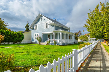 A Victorian cottage with a white picket fence and covered front porch and deck in the Spokane,...