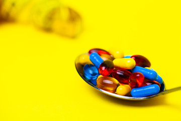 Spoon full of pills for weight loss on a yellow background
