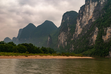Guilin, China - May 10, 2010: Along Li River. Landscape of light brown rocky shoreline in front of...