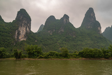 Guilin, China - May 10, 2010: Along Li River. Landscape where tall karst mountains with cliffs seem...