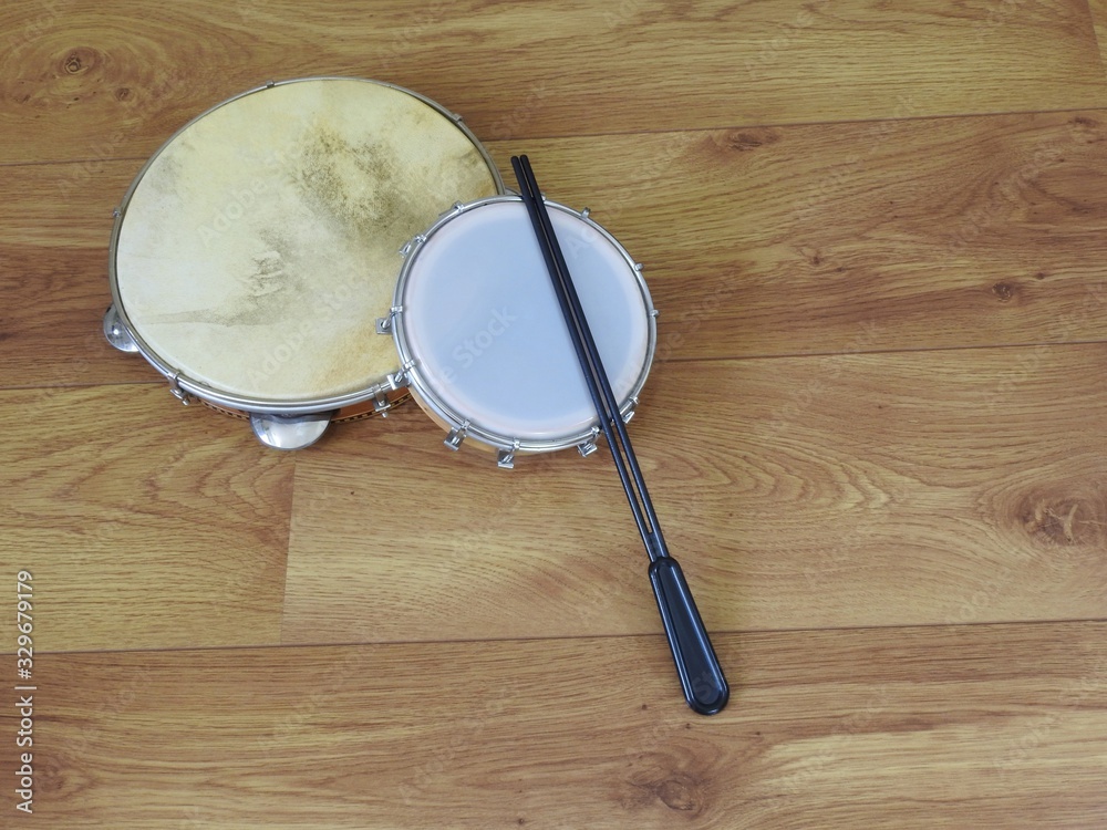 Wall mural Two Brazilian percussion musical instruments: pandeiro (tambourine) and tamborim with drumstick, on a wooden surface. They are widely used in samba and pagode ensembles, popular Brazilian rhythms.