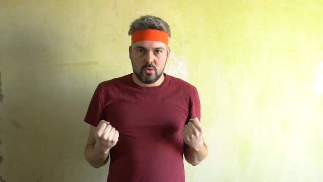 Bearded man against the wall. Good mood. Engaged in martial arts. Repair work in the room. Frick.