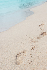 Holiday symbol of quiet rest in attractive areas on the beach, with visible footprints in the sand. Concept for travel vacation - footsteps in sand on summer tropical getaway holidays vacation