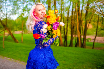 Romantic Caucasian Blond Girl with Bunch of Tulips on Nature Outdoors.