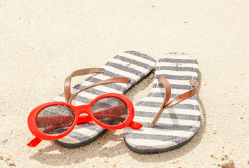 Sunglasses and flip flops on a tropical sand beach. Travel, vacation concept.