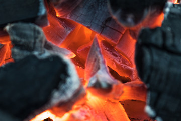 Charcoal burning with orange fire and white and gray ashes preparing for a barbecue in spring and summer