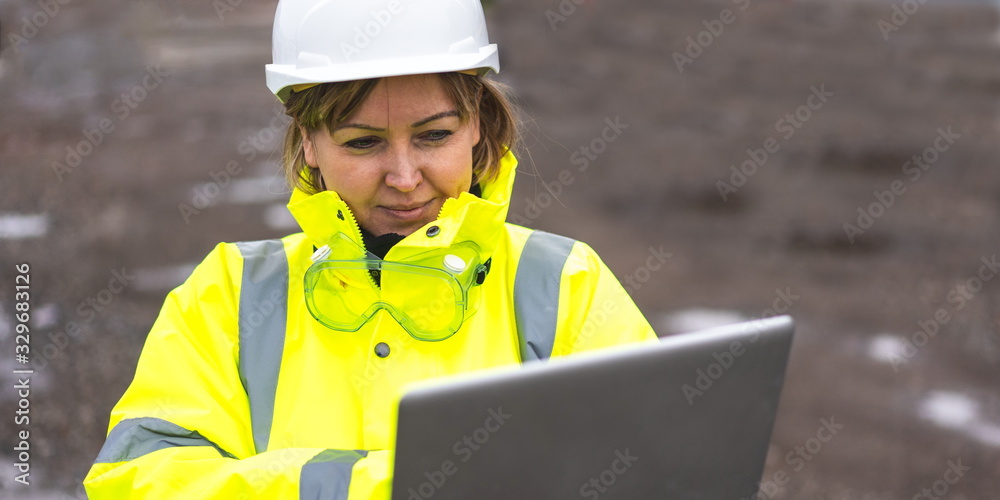 Wall mural woman civil engineer close up. young woman using laptop on construction site. woman engineer develop