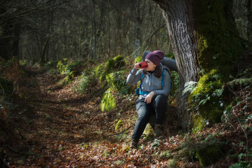 A pilgrim rests sitting drinking from her cup before continuing on the Way of Saint James